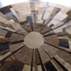 A luxury designer rug tabletop in tan and brown handmade hide, arranged in a radial pattern.