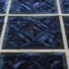Luxury designer rug close-up with geometric blue and black triangles on a high-end custom hide surface.