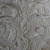 Close-up of high end designer rug Aubusson Hide 16290 with wavy, layered patterns in beige and brown.