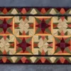 Fancy Hide 16177" luxury designer rug with a geometric star in vibrant tones on dark.