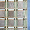 Luxury custom designer rectangular rug in tan, beige, green, and white plaid on gray floor.