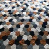 A close-up of a luxury designer rug, showcasing patchwork hide and high-end textures in neutral tones.