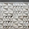 The Esperanza Hide 27929 is a luxury designer rug with geometric triangles in white, gray, and beige on a dark gray floor.