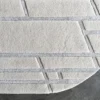 Luxury designer beige and gray geometric handmade silk wool rug with rounded edge on a dark floor.