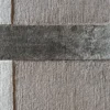 Close-up of a luxury custom designer wool and silk rug, featuring a textured beige base, dark gray stripe, and slim white vertical accents.