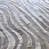 Close-up of a luxury designer rug with curved, interlocking hide pieces in grey and beige.