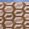 Luxury handmade wool rug with beige geometric hexagons on a brown base, displayed on a gray floor.