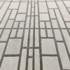 Luxury designer wool rug featuring geometric gray lines on a light background.