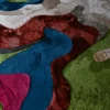 Luxury designer rug with abstract, colorful patches in blue, green, pink, and beige.