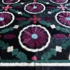 Close-up of Aubusson Hide 16290 luxury designer rug with embroidered floral circles on a dark background.