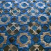 This designer rug features a geometric patchwork of luxe blue, beige, gray, and white squares and diamonds in handmade hide.