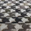 Close-up of luxury designer rug Blackdog Wool 15851, a handmade wool rug with interlocking X pattern in grey, black, brown, and beige.