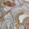 Close-up of a luxury designer rug with textured, overlapping Bloom Hide 16038 in gray, brown, and orange.