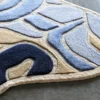 A close-up of the Bloom Silk Wool 30123 handmade designer rug with abstract blue and beige patterns on luxury gray flooring.