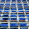 A close-up of a luxury custom rug shows a checkered designer pattern in blue, brown, and tan.