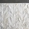 Close-up of a luxury designer handmade hide rug, Lance Hide 14723, in white and gray herringbone on dark floor.