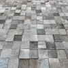 A surface displays luxury designer rugs with high end, textured hide tiles in gray tones.