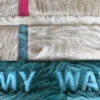 Luxury designer rug with stitched tan and teal panels, “MY WAY” cutout, and colorful accents.