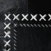 Close-up of luxury custom rug with hand-stitched hide patches in an X pattern, showcasing designer rug craftsmanship.