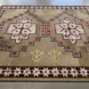 This luxury designer rug showcases geometric star and arrow motifs in tan, pink, brown, and yellow.
