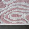 Close-up of the Urushi Wool 28585 luxury designer rug with raised abstract pink and gray pattern on a dark floor.