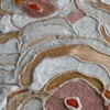 Close-up of Bloom Hide 16038, a high end handmade hide designer rug with abstract beige, gray, pink, and orange patterns.