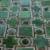 Luxury designer rug featuring geometric green shapes, dark borders, and fur-like textures.