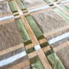 Close-up of luxury designer rug Custom Hide 15284, featuring a handwoven fur grid in brown, beige, green, and white.