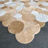 Luxury designer rug with handmade hide, beige and tan circular motifs on gray floor.