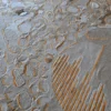Close-up of Hide 29827 luxury designer rug with textured gray surface and gold accents.