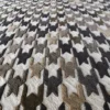A close-up of a high end designer rug in wool, showing a textured houndstooth pattern.