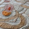 Close-up of luxury designer rug Bloom Hide 16038, featuring handmade hide and wool in beige, brown, gray, and orange organic swirls.