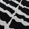 Close-up of a luxury custom designer wool rug in black with organic wavy white stripes.