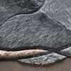 Close-up of a wavy, abstract designer rug with gray, black, and beige faux fur from a luxury custom handmade hide rugs collection.