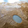 Portal Hide 25165 is a luxury designer rug, handmade from tan and brown hide with an oval cutout.