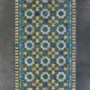 The Crossroads Hide 15073 is a luxury designer rug with a geometric pattern in blue, brown, green, and beige on a dark grey floor.