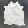 The Broken Hide 15788 is a luxury designer rug, handmade from white hide in an irregular patchwork, displayed on a dark gray floor.