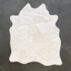 The Broken Hide 15788 luxury designer rug features handmade hide in a white geometric patchwork, displayed on a dark gray floor.
