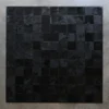 Promenade Hide 30151 square designer rug features black textured handmade hide tiles on a light gray wall.