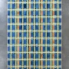 Luxury designer rug with a grid of blue, yellow, and brown on gray hide background.