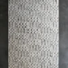 Luxury designer rug with geometric triangles and diamonds in gray tones on dark gray floor.