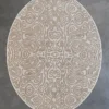 Luxury designer round wool rug with abstract wood grain in beige, on concrete floor.