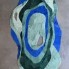 Luxury custom designer rug with abstract blue and green shapes on a light floor.