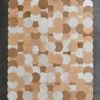 A luxury designer rug with overlapping gold, bronze, and white circles on dark grey, showcasing high-end custom craftsmanship.