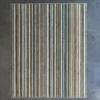 Luxury designer wool rug with blue, beige, green, and white stripes on gray floor.