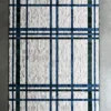 Luxury custom hide designer rug with white texture and blue, green, black grid on concrete floor.