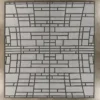 Luxury designer wool rug with black geometric lines on light gray, on brown textured floor.
