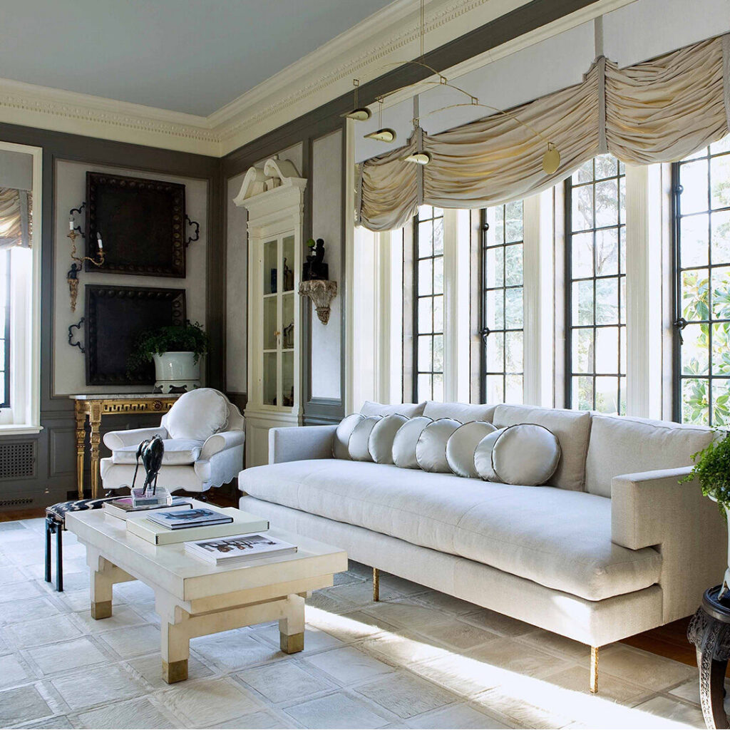 A bright, elegant living room with a beige sofa and luxury designer rug on the floor.