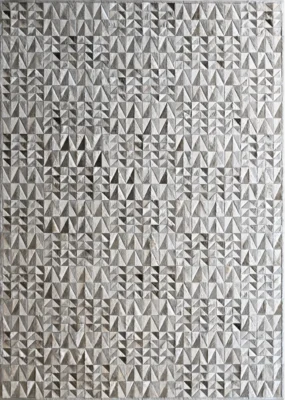 A luxury designer rug with raised triangles forms a textured gray pattern, showcasing high end handmade hide rug craftsmanship.
